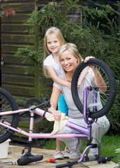 Obraz premium Mother And Daughter Cleaning Bike Together