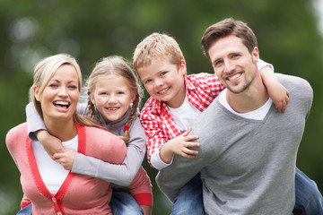 Parents Giving Children Piggybacks In Countryside