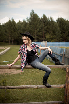 girl wearing jeans and checkered shirt sitting on the fence