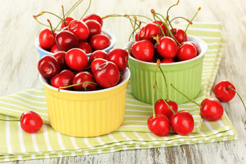 Cherry berries in bowls on wooden table close up