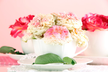 Roses in cups on napkins on pink background