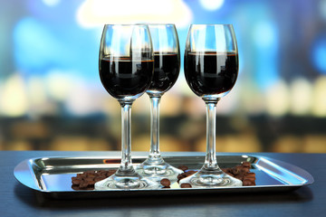 Glasses of liquor on tray,  on bright background