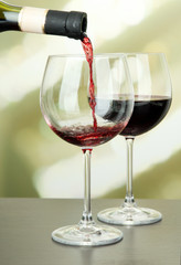 Red wine being poured into wine glass, on bright background