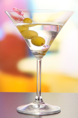 Martini with green olives on table in bar