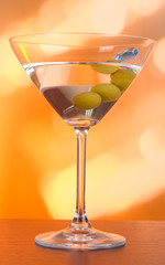 Martini with green olives on table in bar