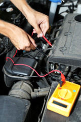 Auto mechanic uses multimeter voltmeter to check voltage level