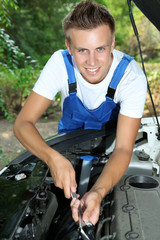 Fototapeta na wymiar Young car mechanic repairing car engine outdoors