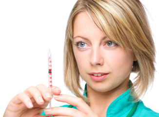 Young nurse is preparing syringe for injection