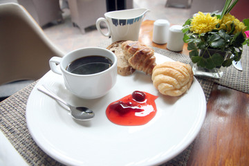 Coffee, bread and jam in white dish.