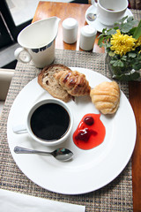Coffee, bread and jam in white dish.