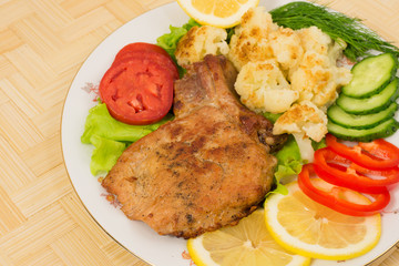 Grilled pork chop with a side dish of cauliflower and vegetables
