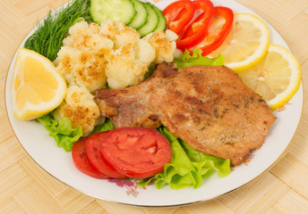 Grilled pork chop with a side dish of cauliflower and vegetables