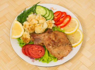 Grilled pork chop with a side dish of cauliflower and vegetables
