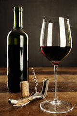 Glass of red wine, corkscrew and bottle on a table