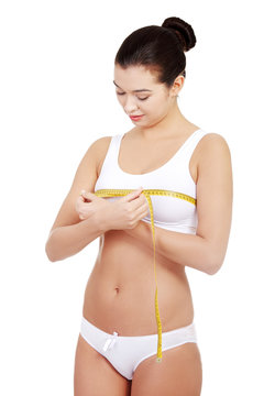 Pretty smiling woman measuring breast with measurement type