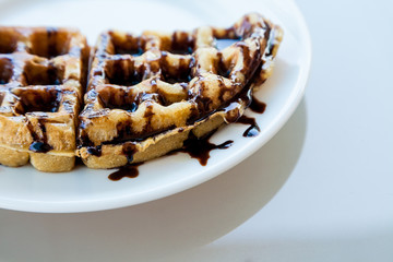 Waffle on white dish with chocolate sauce