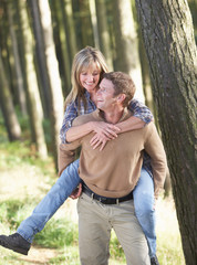 Man Giving Woman Piggyback On Country Walk