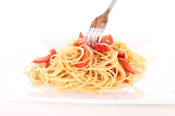 Pasta with tomatoes and garlic being eaten with a fork