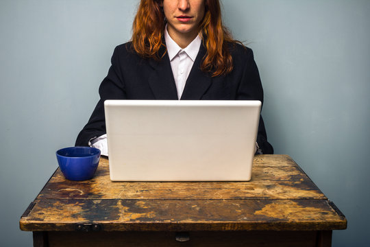 Businesswoman having coffee and working on laptop