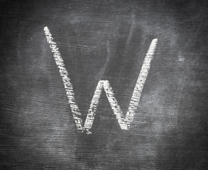W - letter written on black chalkboard.
