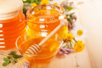 Jar of honey and wooden wand on a wooden background
