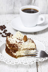 Tiramisu cake on white plate. Wooden background, selective focus