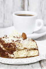 Tiramisu cake on white plate. Wooden background, selective focus