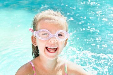 Naklejka premium Pretty smiling little girl in swimming pool