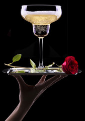 glass of champagne and rose on black