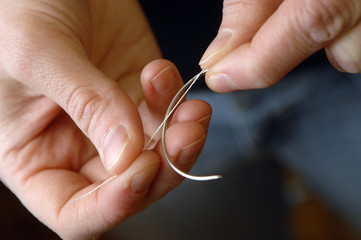 H&auml;nde f&auml;deln einen Faden in eine Buchbindernadel