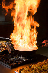 Professional cook preparing food on flame