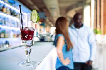 Fruit cocktail with couple blurred in the background.