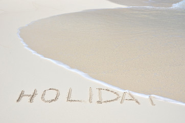 HOLIDAY writing on the sandy beach