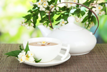 Cup of tea with jasmine, on bamboo mat, on bright background