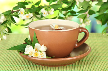 Obraz na płótnie Canvas Cup of tea with jasmine, on bamboo mat, on bright background