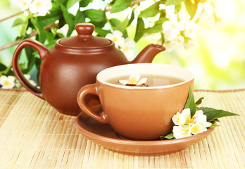 Cup of tea with jasmine, on bamboo mat, on bright background