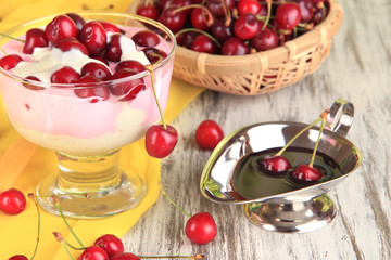 Delicious cherry dessert in glass vase on wooden table close-up