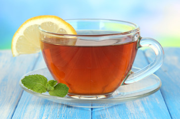 Cup of tea with lemon on table on blue background