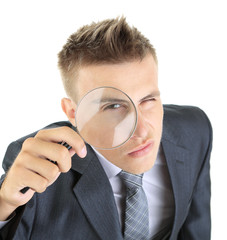 Young businessman looking through magnifying glass isolated