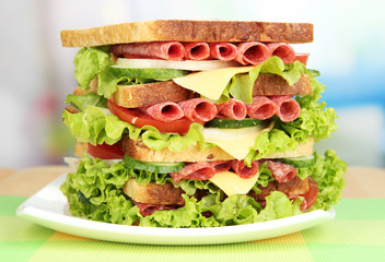 Huge sandwich on wooden table, on bright background