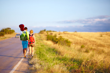 young people traveling hitchhiking. summer field