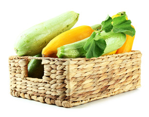 Raw yellow and green zucchini in wicker crate, isolated on