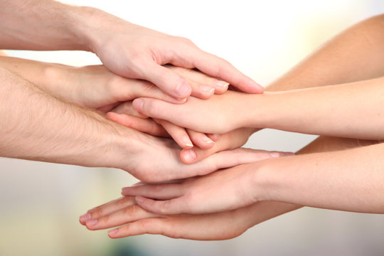 United hands on bright background. Conceptual photo of teamwork