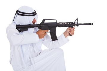 Side view of man aiming rifle against white background