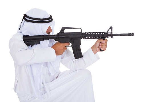 Side view of man aiming rifle against white background