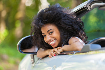 Young black teenage driver seated in her new convertible car - A