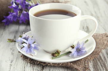 Cup of tea with chicory, on wooden background