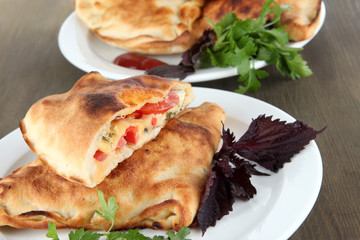 Pizza calzone on plates on wooden table