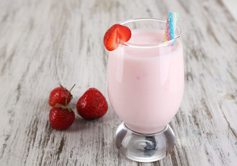 Delicious milk shake with strawberries on wooden table close-up
