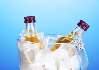Minibar bottles in bucket with ice cubes,  on color background